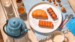 Un esempio de la colazione degli sportivi con merendine assortite, frutta secca, latte e caffè su una tavola in legno